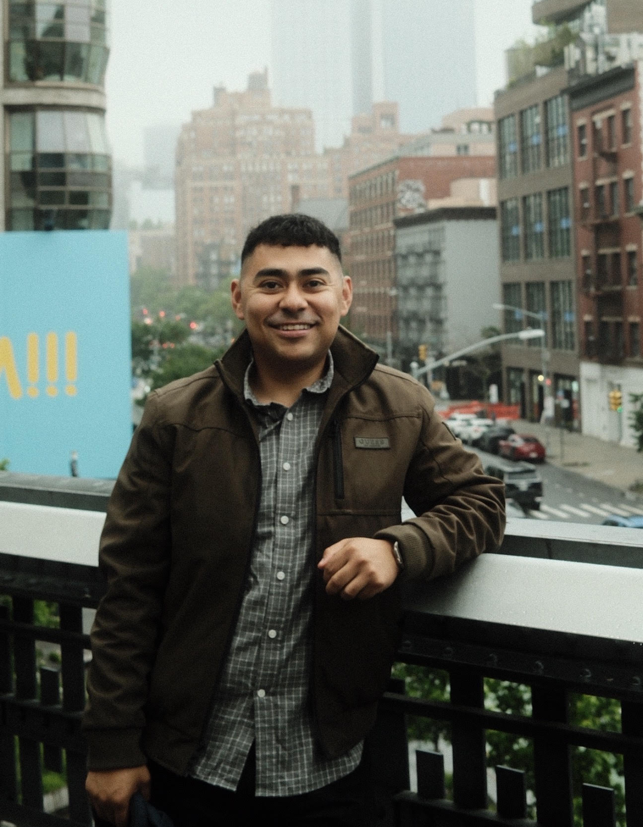 Ivan Palacio leaning against a railing with a city skyline behind him